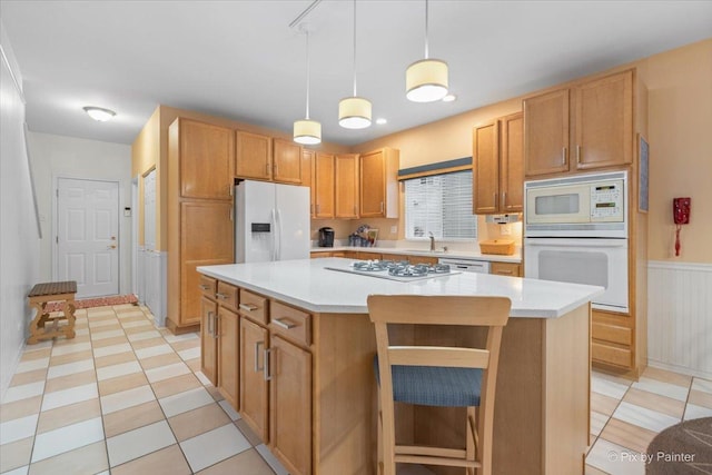 kitchen with sink, white appliances, a kitchen breakfast bar, a kitchen island, and decorative light fixtures