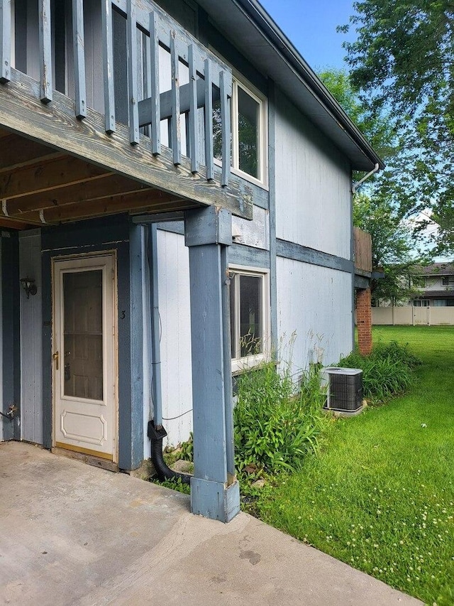 view of side of home featuring a lawn and central AC