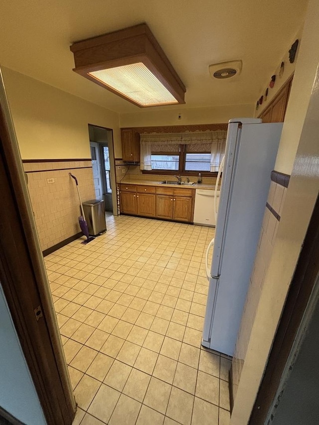 kitchen with light tile patterned floors, white appliances, and sink