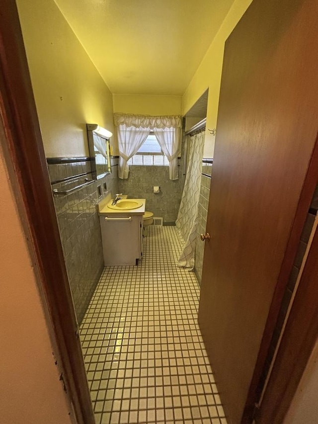 bathroom with tile patterned flooring, tile walls, a shower with shower curtain, vanity, and toilet