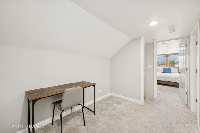 carpeted home office with lofted ceiling and baseboards