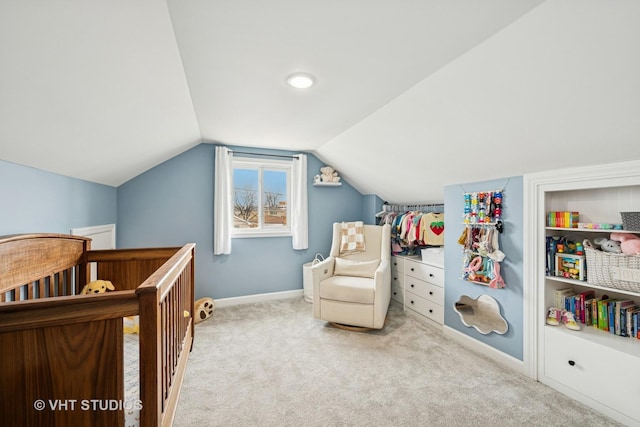 carpeted bedroom with a crib, baseboards, and vaulted ceiling