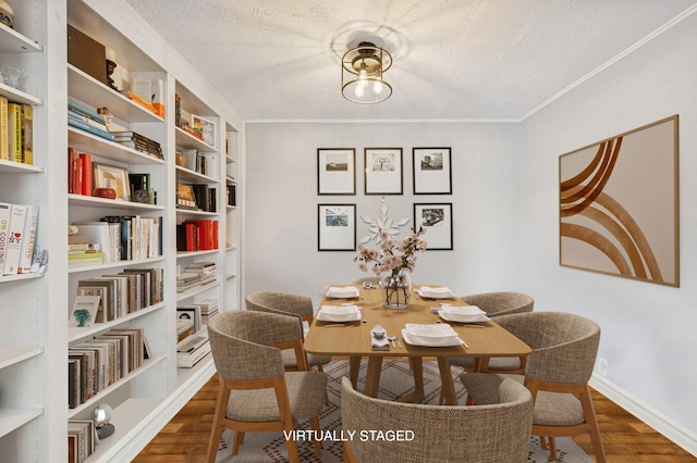 dining room featuring crown molding, baseboards, a textured ceiling, and wood finished floors