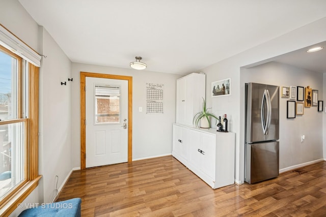 doorway with light wood-type flooring and baseboards