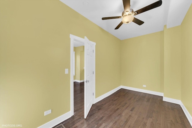 empty room with dark wood-style flooring, a ceiling fan, and baseboards