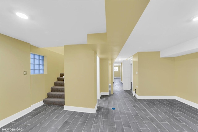 below grade area featuring stairs, wood finish floors, and baseboards