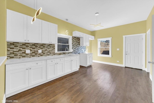 kitchen with dark wood-type flooring, a sink, white cabinetry, light countertops, and backsplash