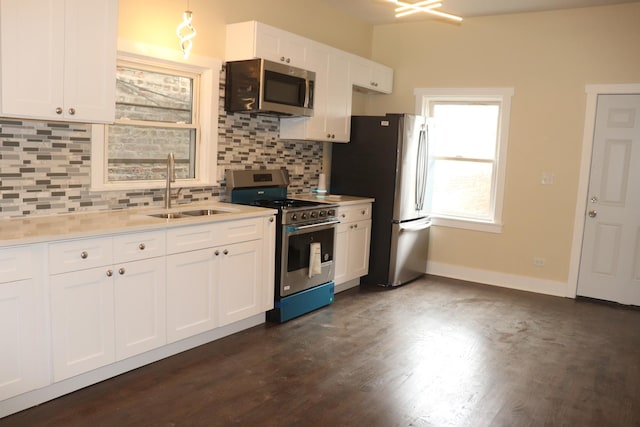 kitchen featuring stainless steel appliances, a sink, white cabinetry, light countertops, and decorative backsplash