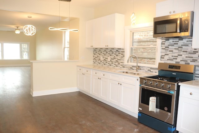 kitchen with white cabinets, decorative backsplash, appliances with stainless steel finishes, light countertops, and a sink