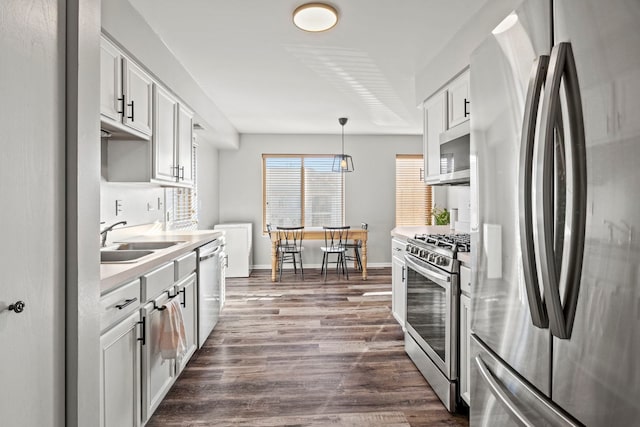 kitchen featuring appliances with stainless steel finishes, pendant lighting, sink, white cabinets, and dark hardwood / wood-style flooring