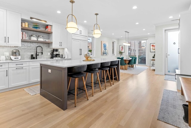 kitchen featuring white cabinetry, decorative light fixtures, paneled built in fridge, a kitchen island, and decorative backsplash