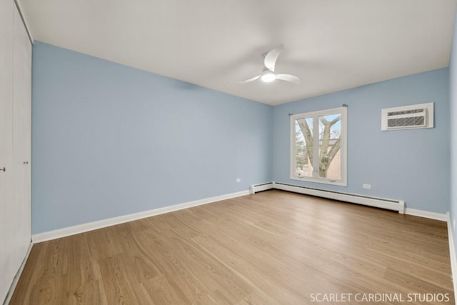 spare room featuring a baseboard radiator, ceiling fan, a wall unit AC, and light hardwood / wood-style floors