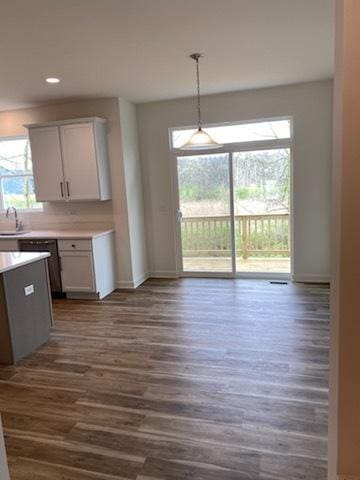 kitchen featuring light countertops, baseboards, a sink, and dark wood finished floors