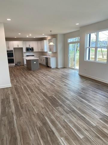 unfurnished living room featuring recessed lighting, baseboards, and dark wood-style flooring