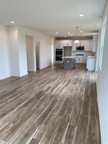 unfurnished living room with dark wood-type flooring, baseboards, and recessed lighting