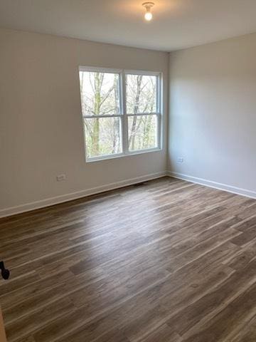 unfurnished room featuring baseboards and dark wood-type flooring