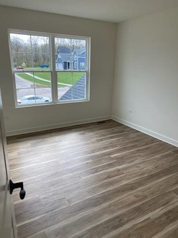 spare room with baseboards and wood finished floors