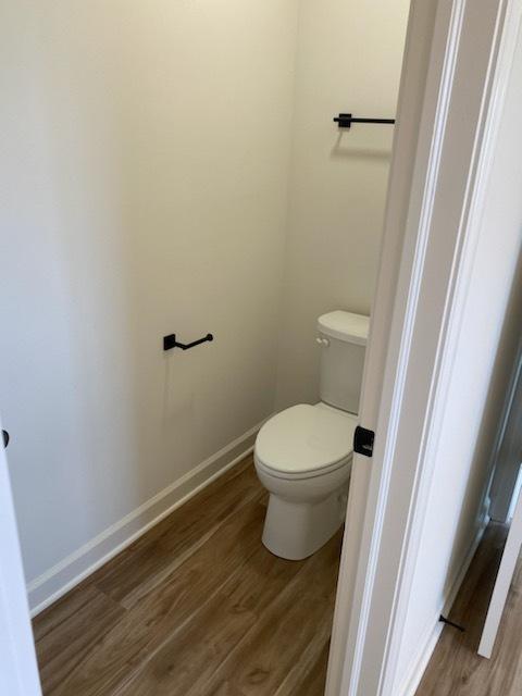bathroom featuring baseboards, wood finished floors, and toilet