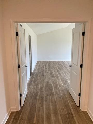 corridor featuring baseboards and dark wood-style flooring