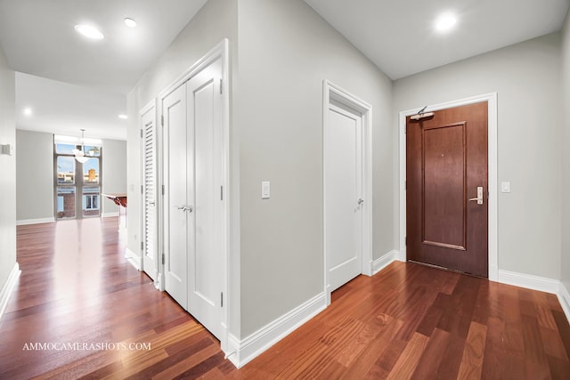 hallway featuring dark wood-type flooring and a chandelier