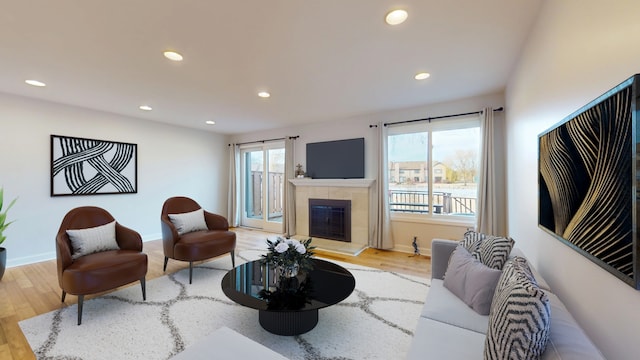 living room featuring a tiled fireplace and light hardwood / wood-style flooring