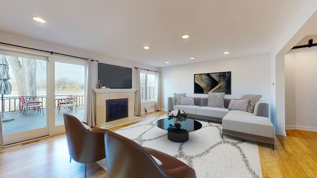 living room with a tiled fireplace and light hardwood / wood-style flooring