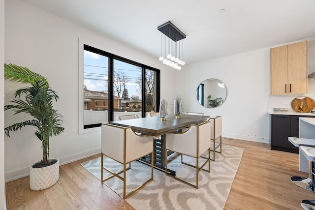 dining area with light wood-type flooring, baseboards, and a chandelier