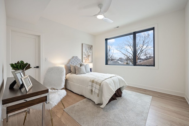 bedroom with baseboards, visible vents, ceiling fan, and light wood finished floors