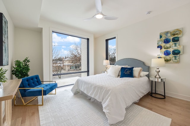 bedroom featuring access to exterior, wood finished floors, a ceiling fan, and baseboards