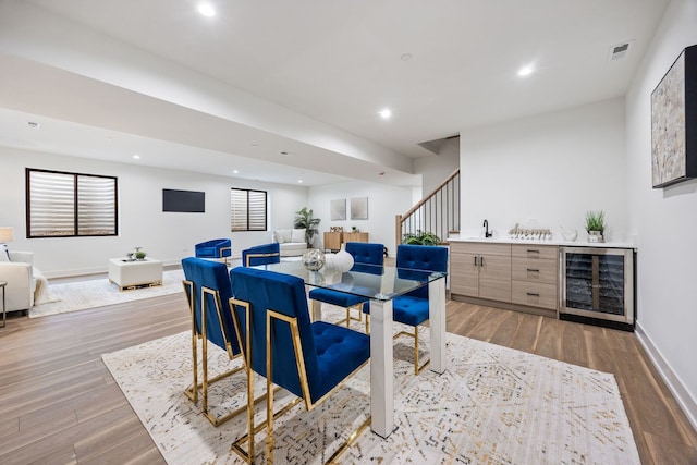 dining room with a bar, light wood-style floors, beverage cooler, and recessed lighting