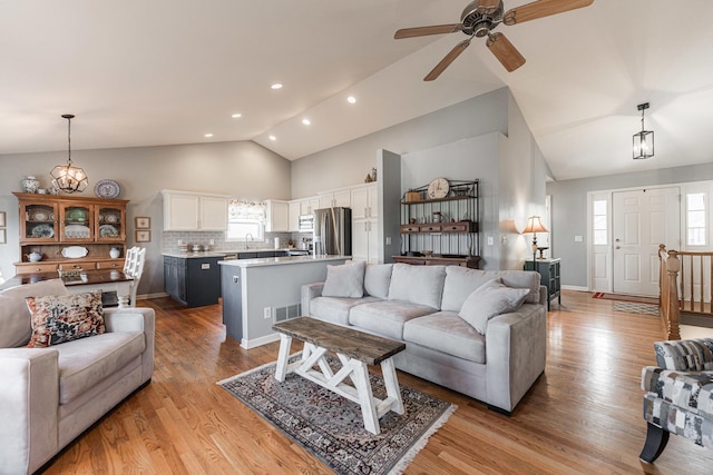 living room featuring sink, ceiling fan, high vaulted ceiling, and light hardwood / wood-style floors