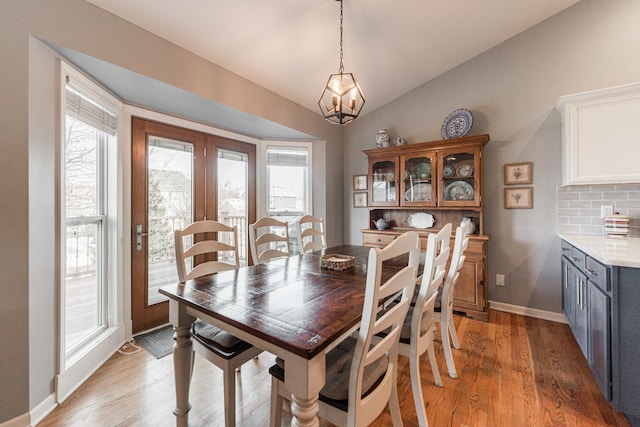 dining area featuring light wood-type flooring, a healthy amount of sunlight, french doors, and lofted ceiling