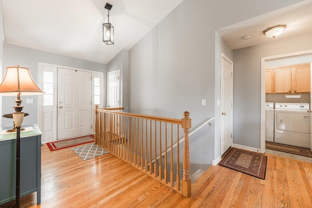 foyer featuring vaulted ceiling, separate washer and dryer, and light hardwood / wood-style floors