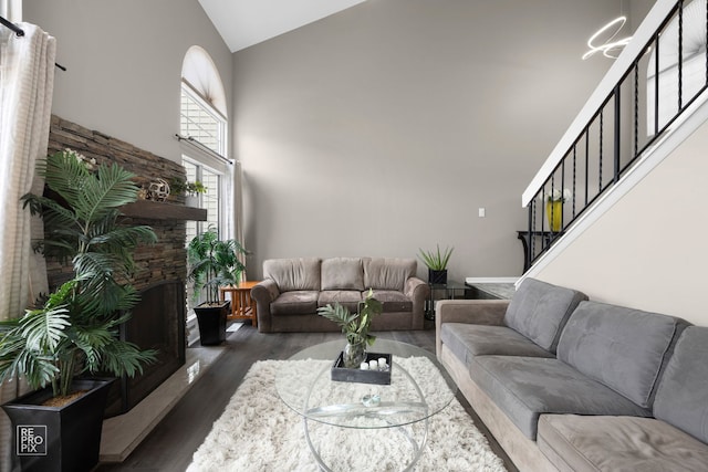 living room with dark hardwood / wood-style flooring, an inviting chandelier, a fireplace, and high vaulted ceiling