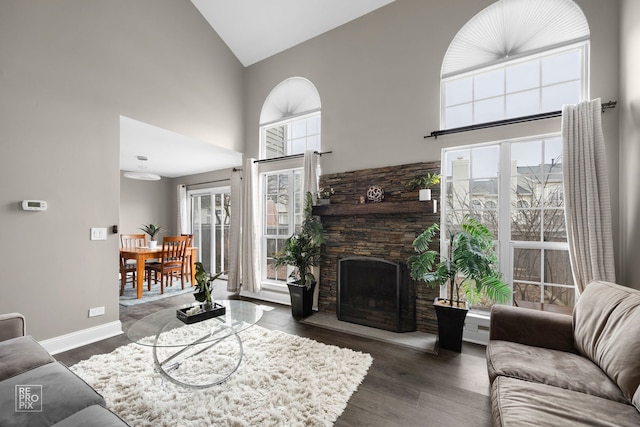 living room with dark hardwood / wood-style flooring, a stone fireplace, and high vaulted ceiling