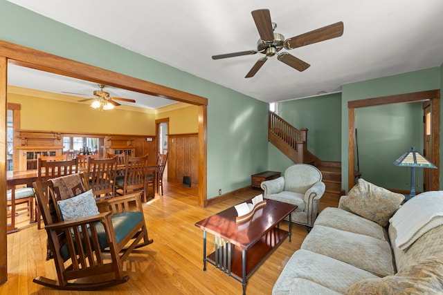 living room with stairway, a ceiling fan, and light wood-style floors