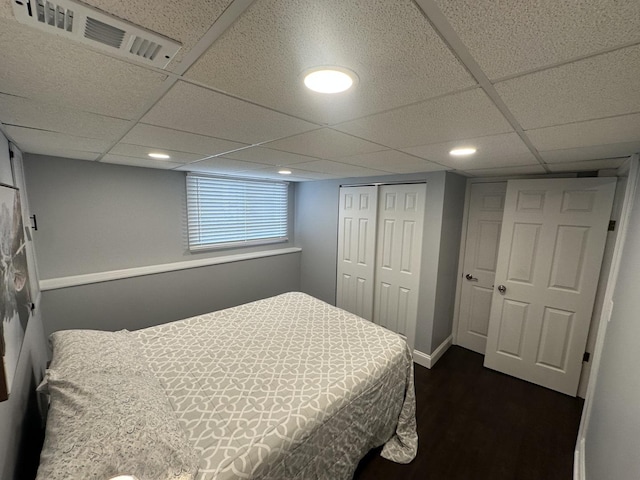 bedroom featuring a paneled ceiling, dark hardwood / wood-style flooring, and a closet