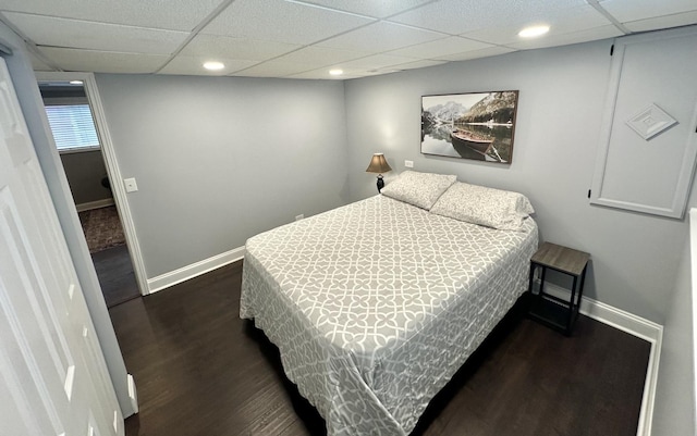 bedroom with a paneled ceiling and dark hardwood / wood-style floors