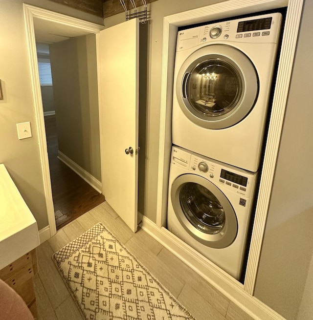 laundry area with hardwood / wood-style flooring and stacked washing maching and dryer