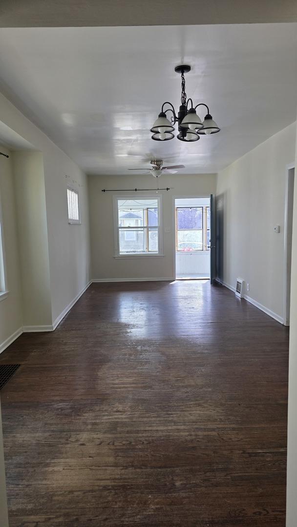 unfurnished room with dark wood-type flooring and an inviting chandelier