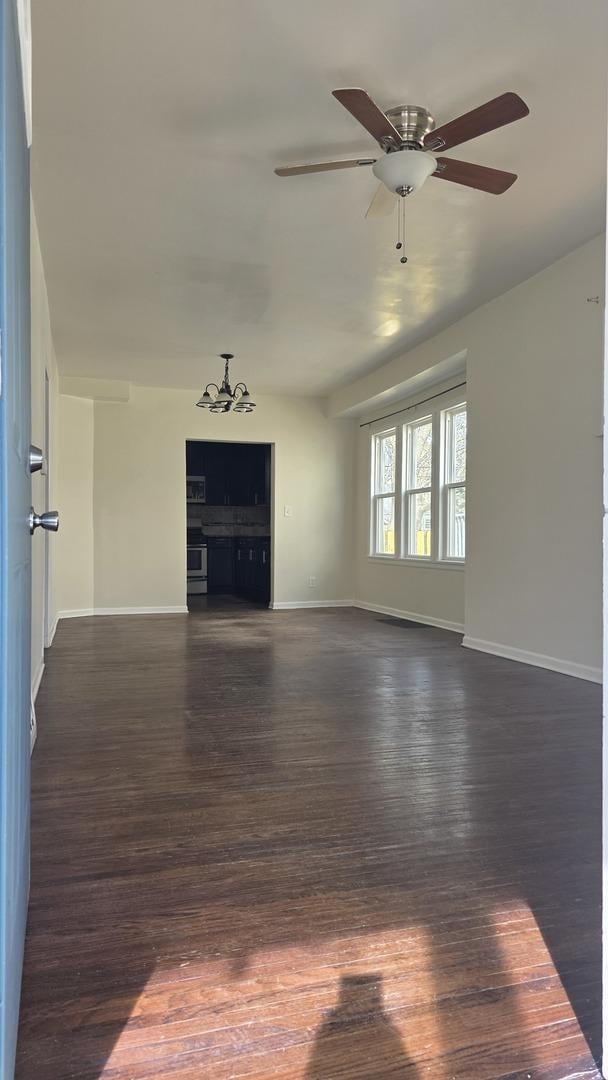 unfurnished living room with dark hardwood / wood-style flooring and ceiling fan with notable chandelier