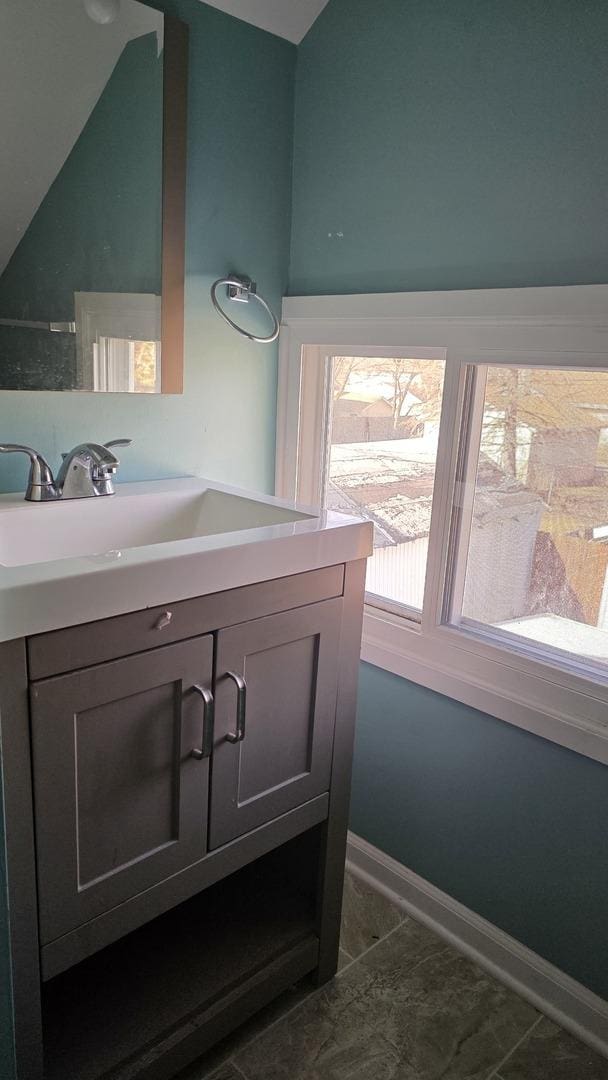 bathroom with tile patterned flooring, vanity, and vaulted ceiling