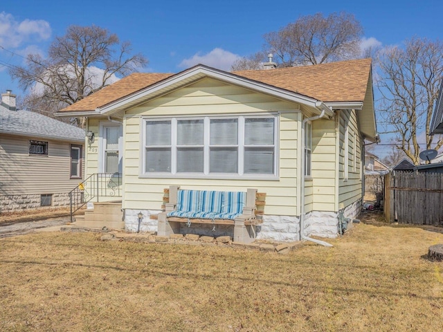 exterior space featuring roof with shingles, a lawn, and fence