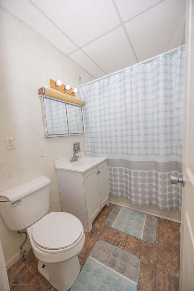 bathroom featuring a shower with shower curtain, vanity, toilet, and a drop ceiling