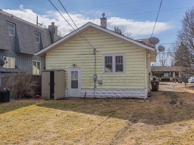 rear view of property featuring a shingled roof and a yard