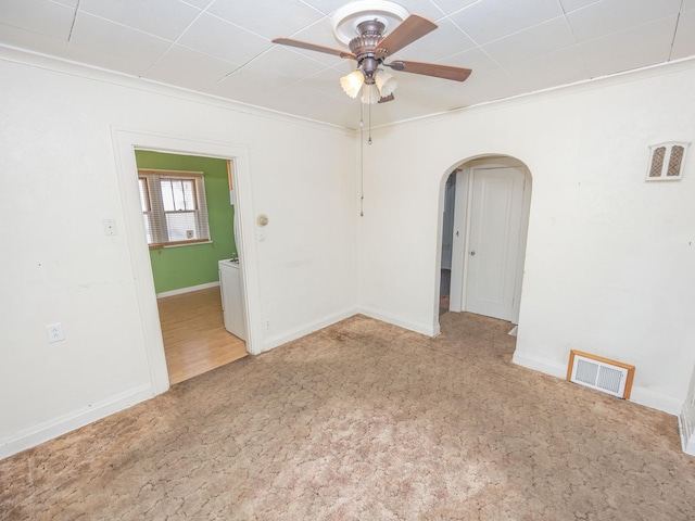 spare room with arched walkways, carpet, visible vents, and a ceiling fan