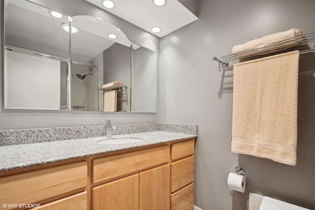 bathroom featuring vanity, a shower with door, and toilet