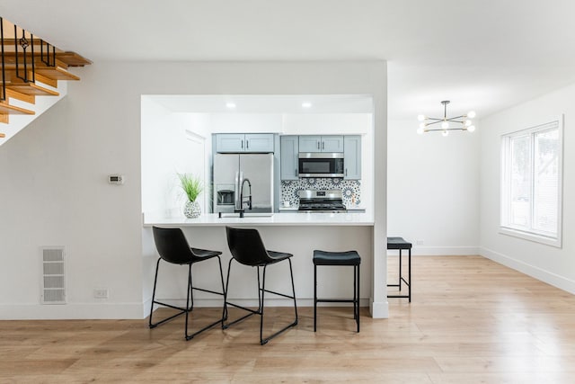 kitchen with tasteful backsplash, a breakfast bar, kitchen peninsula, and appliances with stainless steel finishes