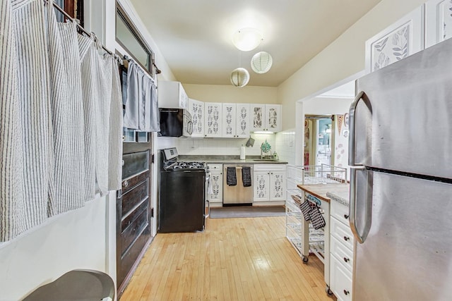 kitchen with sink, light wood-type flooring, white cabinets, stainless steel appliances, and backsplash