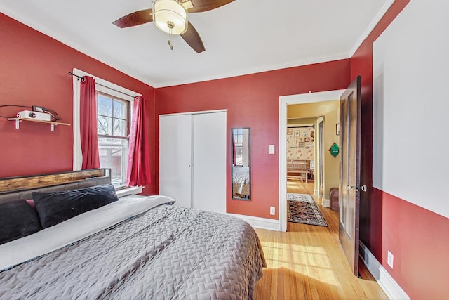 bedroom with ceiling fan, ornamental molding, light hardwood / wood-style floors, and a closet